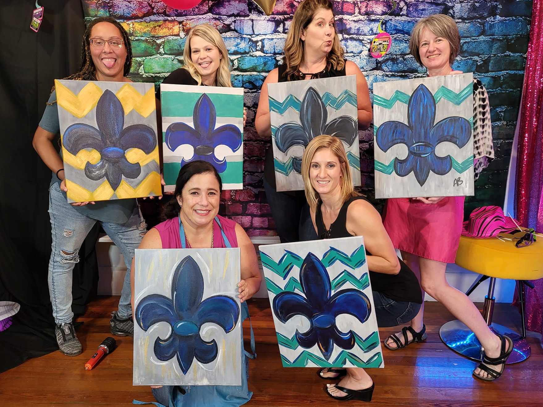 Guests posing with colorful paint party artwork and selfie station backdrop at Lafayette Paint Party in Lafayette Louisiana
